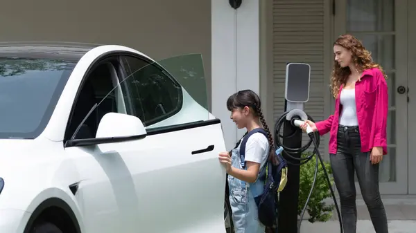 幸せな小さな少女は 母親がEv充電ステーションから電気自動車を充電するのを助けるため 環境にやさしいエネルギーの持続可能性について学びます Ev車とモダンファミリー パノラマシンクロノス — ストック写真