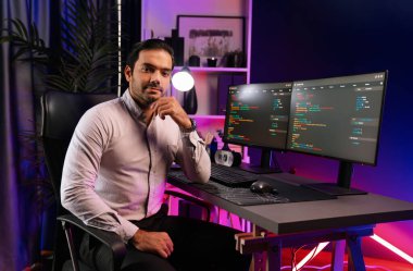 Bilgisayar ekranındaki yazılım geliştirme kodlamasına karşı poz vermek için akıllı bilişim geliştirici görünümlü kamera profilleri, neon ışıklı siber oda ofisinde program güncellemesi internet sitesi verileri sunuyor. Tahmin et..