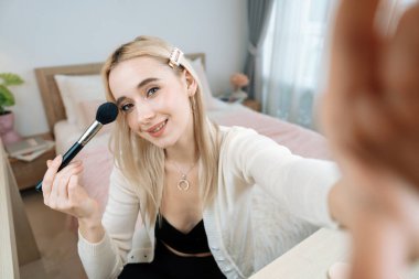 Sosyal medya için güzellik ve kozmetik video içeriği hazırlayan genç bir kadın. Güzellik blogcusu, seyircilere ve takipçilere rimel sürmeyi öğretirken kameraya gülümsüyor. Blithe