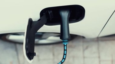 Elektrik yükleme istasyonundan parlayan ışık kablosu ile elektrik şarj etmek için elektrikli araca takılı üst görüntü EV şarj cihazı. Kesme-Sınır yeniliği ve gelecekteki yeşil enerji sürdürülebilirliği. İnceleyin