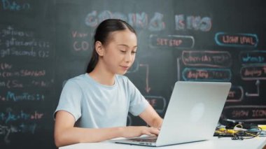 Kara tahtada dizüstü bilgisayar kullanarak akıllı kız programlama sistemi. Lise öğrencisi mühendislik kodları yazıyor ya da STEM teknoloji sınıfındaki kameraya bakarken bir şey söylüyor. Yaratıcı eğitim. Öğretim