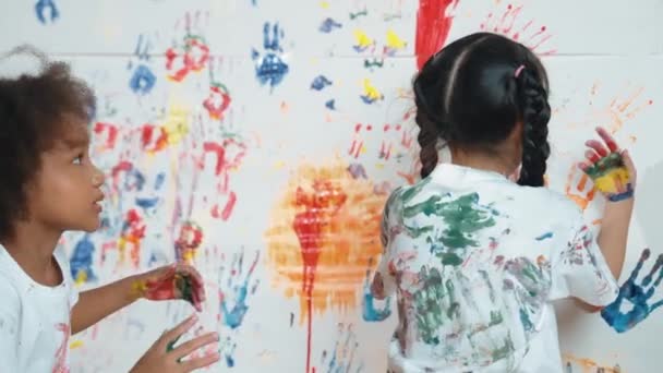 カラフルなステンドウォールの近くには アートクラスの学生が描きました おかしいアジアの少女は 混乱した部屋で多様な子供たちとカラフルな水彩で遊んでいます クリエイティブ活動コンセプト エラー — ストック動画