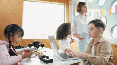 Akıllı öğretmen öğrencilere elektrikli aletin bir kısmını açıklamak için cam tahta kullanıyor. Çeşitli çocuklar elektronik aletleri öğrenir ve ana kartı ya da robotu tamir ederken dizüstü bilgisayar kullanır. Etkinlik.