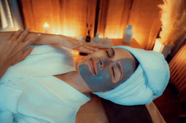 Kaplıca salonunun sakin atmosferi, üst düzey kadın müşteri sıcak mum ışığında kömür kömürü yüz kremi masajıyla kendini yenilemeye çalışıyor. Yüz bakımı ve güzellik konsepti. Sessiz.