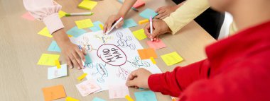 Yaratıcı iş adamları, zihin haritalama kullanarak pazarlama stratejisi ve iş planı hakkında beyin fırtınası yapıyorlar. Girişim ekibi kağıda yazmak için birlikte çalışır. Eline odaklan. - Yakın çekim. Değiştirilmiş.