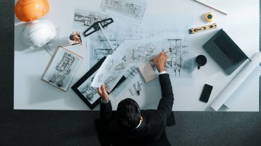 Yetenekli inşaat mühendisinin ev modeline bakarken oturup fikir yazması. Mimarın ya da tasarımcının yaratıcı bina inşaatını planlama ve düşünme havadan görünüşü. Hizalama.