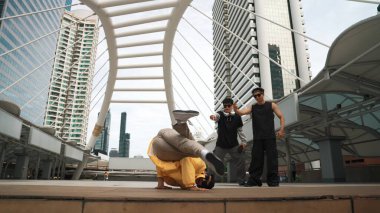 Bir grup profesyonel sokak dansçısı neşelen Asyalı hippi şehirde serbest dans ederken düşük açılı kamerayla çevrili insanlar tarafından. Break dans konsepti. Açık hava sporu 2024. Yumuşak bir şekilde..