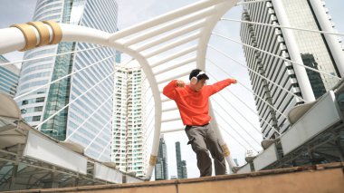 Şehre atlarken kulaklık takan Asyalı hippi. Profesyonel break dansçı şehirde break dans gösterisi yapıyor. Break dans ya da sokak dansı. Açık hava sporu 2024. Yumuşak bir şekilde..