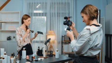 Etkilenen iki ortak canlı yayında video görüntülerini çekiyor makyaj malzemesi prim sosyal medya veya blog. Kozmetik stüdyosu ışıklandırmalı mutlu genç kız çevrimiçi pazarlama oturumu yayını için..