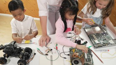 Kafkas öğretmeninin çeşitli öğrencilere elektronik yönetim kurulunu öğretmesi. Çok kültürlü çocuklar dijital elektrikli aletleri ve ana kartı çip ve kablolar kullanarak tamir etmeyi öğrenirler. Etkinlik.