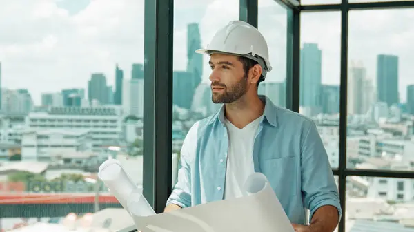 Professional architect engineer or male worker in casual outfit looking at skyscraper and city view while holding project plan. Creative design, civil engineering, building construction. Tracery