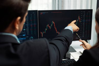 Dinamik borsada döviz kuru yatırımını tartışan iki ticaret simsarı iki bilgisayar ekranında gerçek zamanlı risk grafiği ya da modern ofisteki kar noktasını karşılaştırıyor. Varsayım.