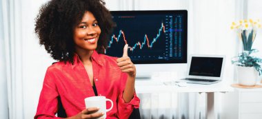 Analytical young African American businesswoman, a specialist in successful stock exchange trading, against dynamic data graph displaying marketing trend analysis on screen. Tastemaker. clipart