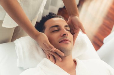 Beyaz adam stres önleyici kafa masajından ve lüks bir tatil beldesi veya otel spa salonundaki modern ışık ortamında yüz güzelliği eğlencelerini şımartmaktan hoşlanıyor. Sessiz.