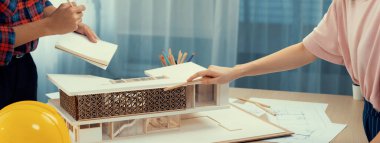 Akıllı mimar mühendis ve iç mimar birlikte çalışıyor ve ev modelini ölçmek için plan ve mimari ekipmanlarla toplantı masasında cetvel kullanıyor. Takım çalışması konsepti. Filizlenen.