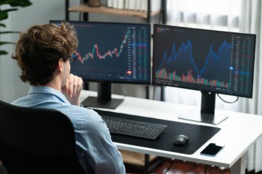 Modern ofiste arka tarafı olan iki bilgisayar ekranında gerçek zamanlı olarak piyasa dinamik grafik verileri üzerinde çalışan genç bir tüccar. Dinamik para bozdurma oranını analiz etme kavramı. Toplayıcı.