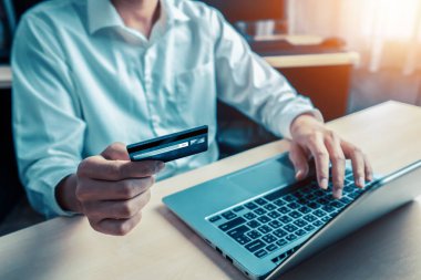 Genç adam, laptop bilgisayar başvurusu ya da web sitesinde online alışveriş yapmak için kredi kartı kullanıyor. E-ticaret ve online alışveriş konsepti. uds