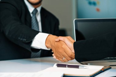 İş adamları konsepti kabul ediyor. İş adamı ve Asyalı iş kadını ofiste el sıkışırlar. uds