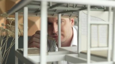 Kafkasyalı mimar mühendisinin yakın çekimi ev inşaatını denetlemek ve bina malzemelerini kontrol etmek. Proje yöneticisi modele dikkatlice bakarken kalemi işaret ediyor. Yönlendirici.