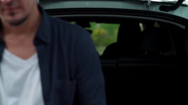 Ulusal Park veya Yaz Ormanı 'ndaki tatil gezisi sırasında EV şarj istasyonundan elektrik aküsü almak için akıllı telefon internet bankacılık uygulaması kullanan bir adam. Yükselt