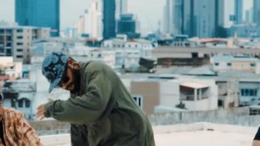Çatıda çok kültürlü arkadaşlar varken profesyonel İspanyol break dansçısı B boy dansı. Genç modern dans grubu hip hop hareketi yapıyor. Tarz, moda, aksiyon. Açık hava sporu 2024 hiphop..