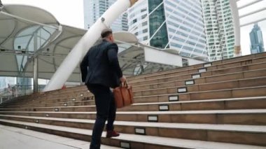 Kafkasyalı zeki işadamı şehir manzarası ile çevrili merdivenleri çıkıyor. Hırslı proje yöneticisinin modern inşaatta zorlu bir iş ya da yatırım fırsatı bulması. Urbane.