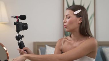 Sosyal medya için güzellik ve kozmetik video içeriği hazırlayan genç bir kadın. Güzellik blogcusu kameraya gülümserken seyircilere ve takipçilere güzellik bakımını gösteriyor. Düzenle