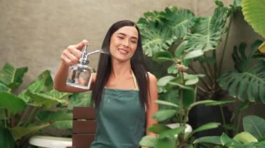 Genç kadın bahçıvan, minimalist mimari beton tarzında tropikal bitkilerle ilgileniyor ve onları suluyor. Yaz mevsiminde egzotik bitki yetiştirme bahçeleri, çevreci yaşam tarzları için bahçeler. Blithe