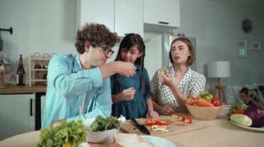 Çekici beyaz anne ve baba Asyalı kızıyla taze yemek pişirmek için birlikte vakit geçiriyorlar. Annem ve babam mutfakta salata yapmak ve sebze yemek için taze sebze hazırlıyorlar. Pedagoji.
