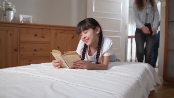 幸せな現代の家族は週末に小さな女の子を起こし 遊び心のあるタックルは 彼らの若い娘への愛と愛情を表現し 笑顔で一緒に ファスティオディオス — ストック動画