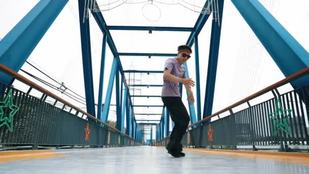 希波斯特在有背景的桥上表演男孩步法和街舞 专业的霹雳舞者穿着时髦的衣服 在镜头前摆姿势时看着镜头 2024年户外运动 神气活现 — 图库视频影像