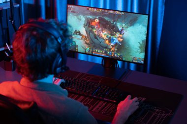Savaş arenasında çoklu oyunlar takımıyla Moba 'da savaşan genç oyun flamasının sunucu kanalı, neon dijital ışık modern odasındaki arka görüntü ile bilgisayar monitöründe kulaklık takıyor. Toplayıcı.