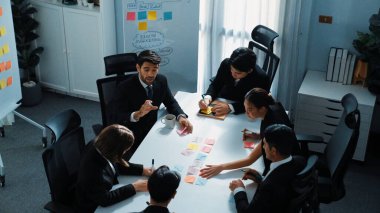 İş adamlarının toplantı odasında pazarlama stratejisi planlarken yapışkan notlar kullanarak beyin fırtınası yapma fikrine en iyi bakış açısı. Çeşitli takımlar mali planı tartışıyor. Takım çalışması konsepti. Müdürlük.