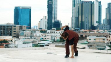 Profesyonel Asyalı break dansçı B çocuk dansı yaparken çatıda çok kültürlü arkadaşlar var. Genç modern dans grubu hip hop hareketi yapıyor. Tarz, moda, aksiyon. Açık hava sporu 2024. ÇalışmaComment.