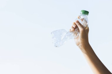 Geri dönüşümlü plastik şişe gökyüzü arka planında el ele tutulur. Geri dönüşüm için plastik atık bulundurmak etkili geri dönüşüm yönetimi ile temiz çevreyi desteklemek için konsepti azaltmak ve yeniden kullanmak. Döngü