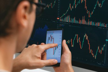 Akıllı borsa yatırımcıları ekranda akıllı telefon ile piyasa borsasını işaret ederek dizüstü bilgisayarın yanı sıra en yüksek dinamik yatırım oranını göstererek, modern işyerindeki veri planlamasına odaklanıyorlar. Bireysel.