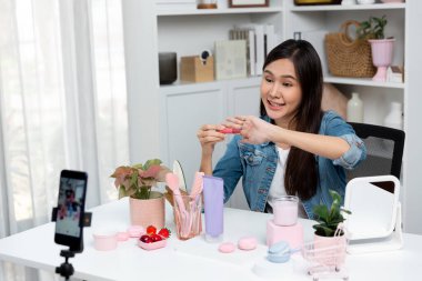 Genç, güzel Asyalı kozmetik makyaj ruju matte pastel rengini modern odadaki sosyal medyada kol testi tanıtımında en çok satanlar listesinde gösteriyor. Taktik.