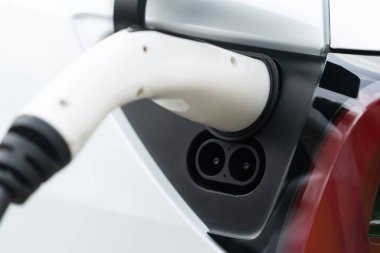 Elektrikli araç portuna bağlı EV şarj prizi kolu şarj istasyonundan şarj oluyor. Modern tasarlanmış EV araba ve daha iyi bir gelecek konsepti için temiz enerji sürdürülebilirliği. Eşzamanlama