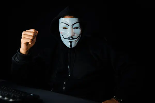 ホワイト笑顔の犯罪者匿名のマスクは カメラを上げて メインのデータベースサーバーシステムを介してウイルスの暗号化をインストールし コンピュータの身代金会社のプライバシーを守ります サーモス — ストック写真