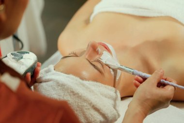 Güzel genç kadınlar profesyonel doktordan yüz masajı alırken spa yatağında yatarlar. Cildi elektrikli yüz makinesiyle çevrili çekici bir kadın. Huzur.