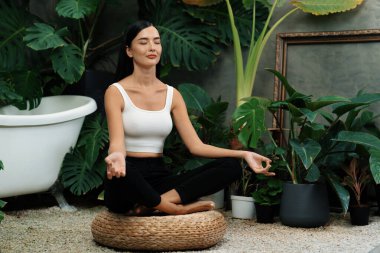 Sabah yoga ve meditasyon yapan genç bir kadın bitki yaprağıyla doğal bahçede yalnızlığın tadını çıkarıyor ve meditasyon yapıyor. Farkındalık aktivitesi ve sağlıklı zihin yaşam tarzı. Blithe