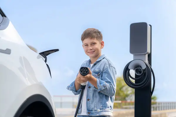 Zabawny Chłopczyk Celujący Kamerę Ładowarką Ładujący Ekologiczny Samochód Elektryczny Stacji — Zdjęcie stockowe