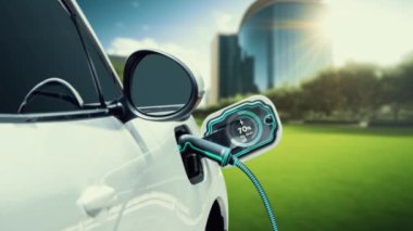 EV otomobili, elektrik yükleme istasyonuna bağlanarak yeşil parktaki EV şarj cihazının pil durumu hologramını şehrin gelecekteki ekolojik yaşam biçimi ve temiz enerjinin kullanımı olarak gösteriyor. İnceleyin