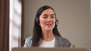 Kadın çağrı merkezi operatörü ya da müşteri hizmetleri çalışanı, müşteriye yardım etmek için kulaklıkla konuşurken çalışma alanı üzerinde çalışıyor. Profesyonel modern iş hizmeti. Blithe