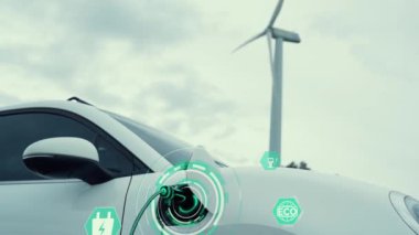 Elektrikli araba, EV şarj istasyonundan enerji alıyor. Rüzgar türbini çiftliğinde EV şarj kablosu kablosunun fütüristik akıllı batarya durum hologramını gösteriyor. Alternatif temiz enerji sürdürülebilirliği. İnceleyin
