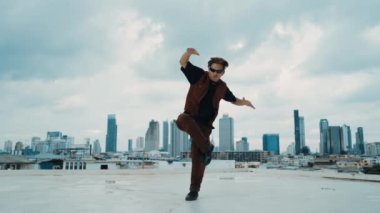 B-boy dans gösterisi profesyonel sokak dansçısı çatıda gökyüzü dövüşçüsüyle, şehir manzaralı. Çekici Asyalı hippi gösterisi, hareketli adımlar. Açık hava sporu 2024. Hip-hop tarzı. hiphop.