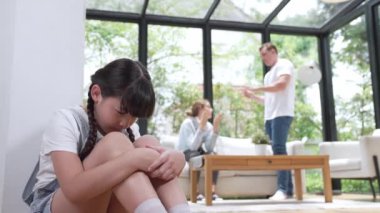 Stresli ve mutsuz genç kız köşeye kıvrılıp kulaklarını kapatarak arka planda ebeveyninin tartışmasını engelliyor. Evde aile içi şiddet ve travmatik çocukluk depresyona dönüşür. Titiz