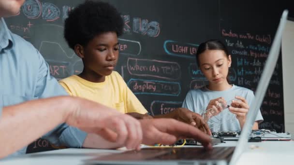 在Stem课上 年轻的学生在老师编程工程代码的同时固定控制器 在聪明女孩使用电子工具和黑板的情况下 教练手打字计算机的关机 — 图库视频影像