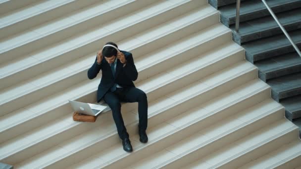 Merdivenlerde Otururken Kulaklıktan Müzik Dinleyen Zeki Bir Adamı Mutlu Menajer — Stok video