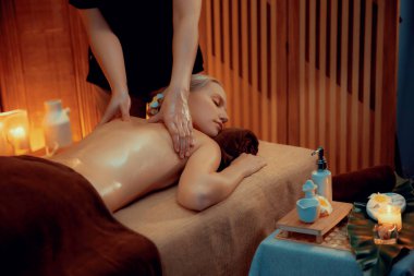 Beyaz kadın müşteri stres önleyici spa masajının keyfini çıkarıyor ve lüks otel ya da otelde sıcak mum ışığında güzellik teniyle eğleniyor. Sessiz.